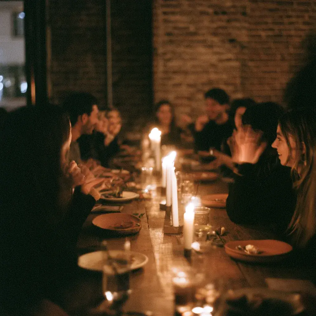 Guests laughing around a long candlelit table at a founder dinner